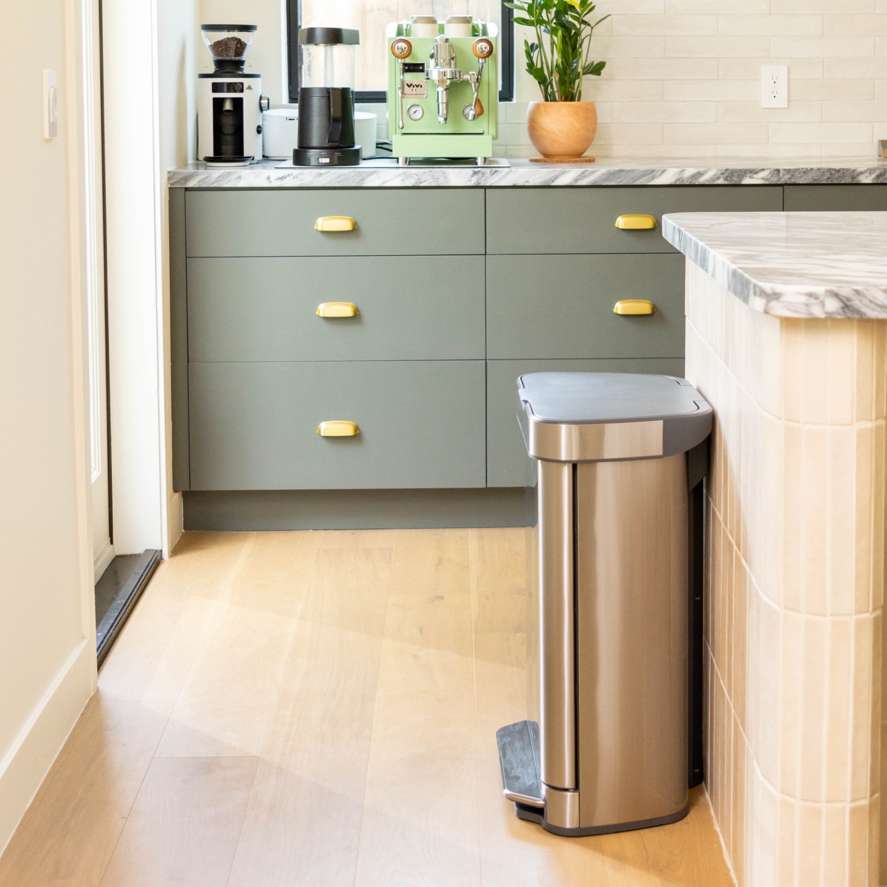 The Pulli Bin Step beside green kitchen cabinets